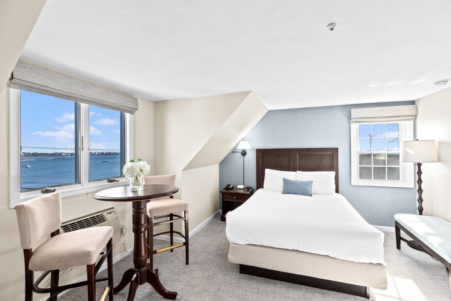 Cozy bedroom with a large window, sea view, and small dining area.