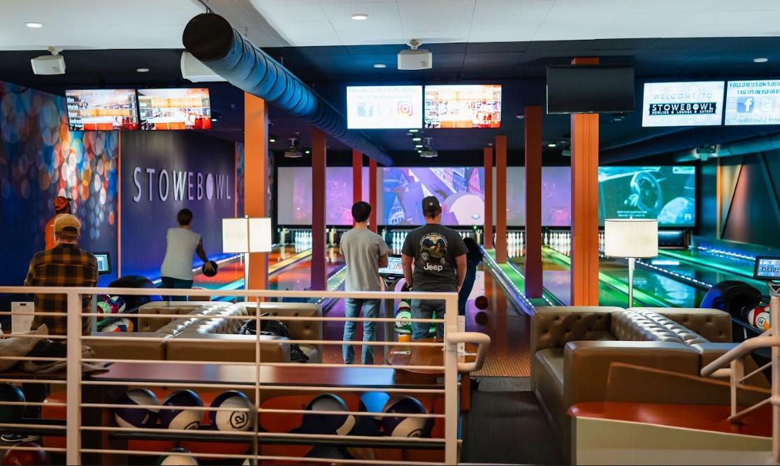 Bowling alley with people playing and colorful lights.
