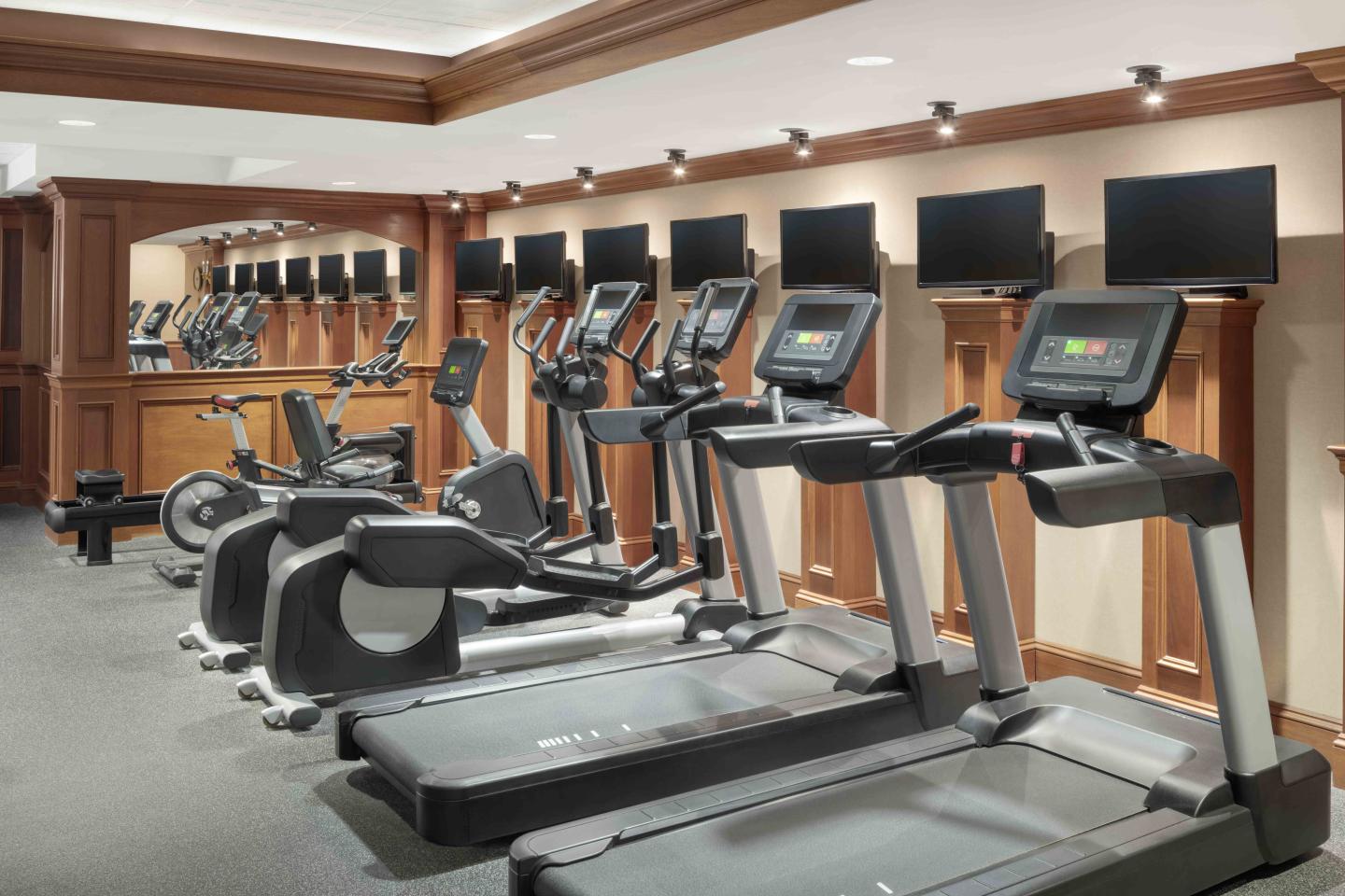 Rows of treadmills and exercise bikes in a well-lit gym.