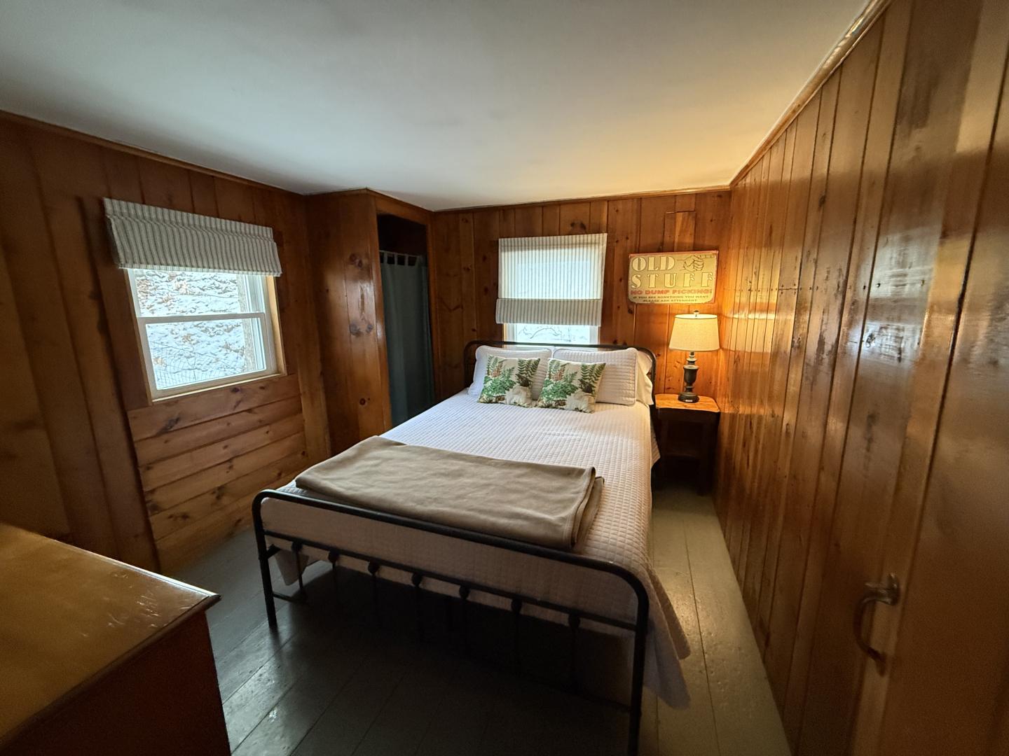 Cozy wood-paneled bedroom with a bed, nightstand, and lamp.