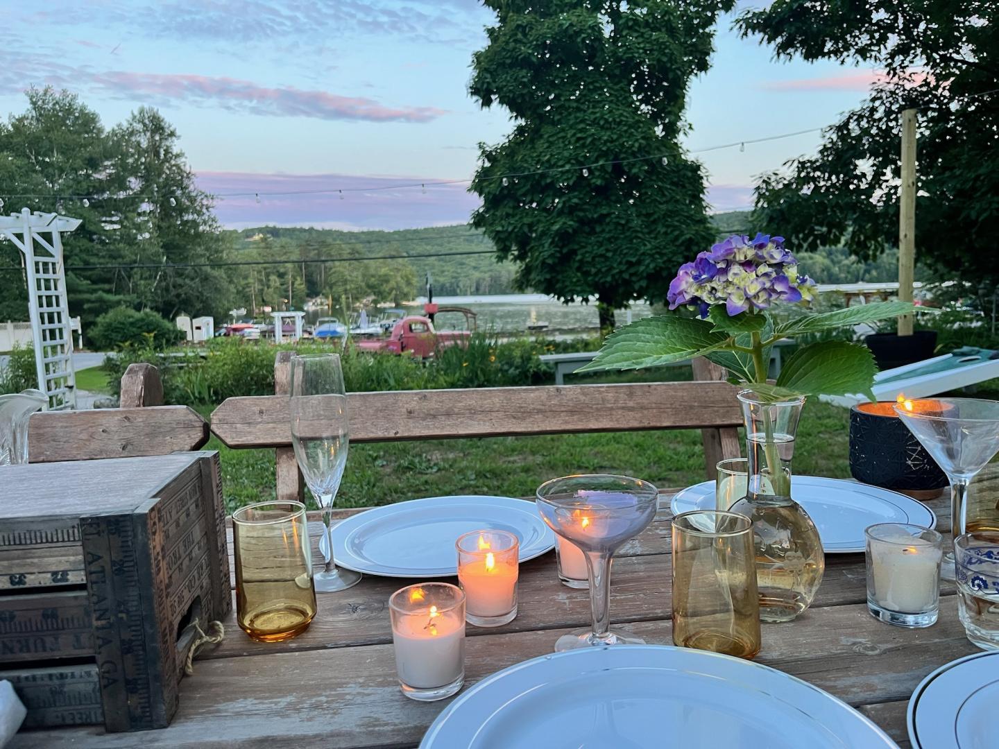 Outdoor table setting with candles and flowers, overlooking a green landscape.