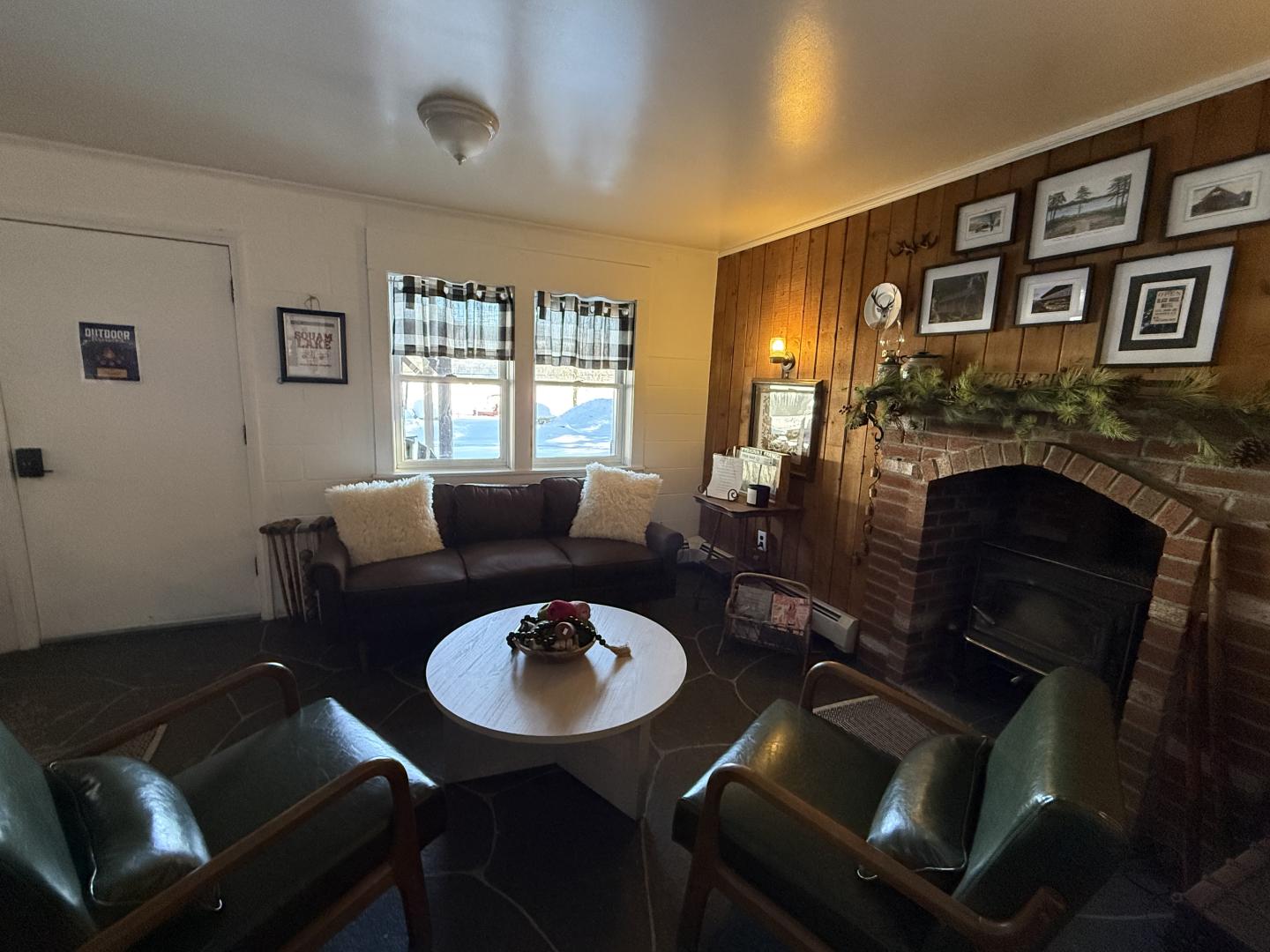 Cozy living room with sofas, a brick fireplace, and framed pictures on the wall.