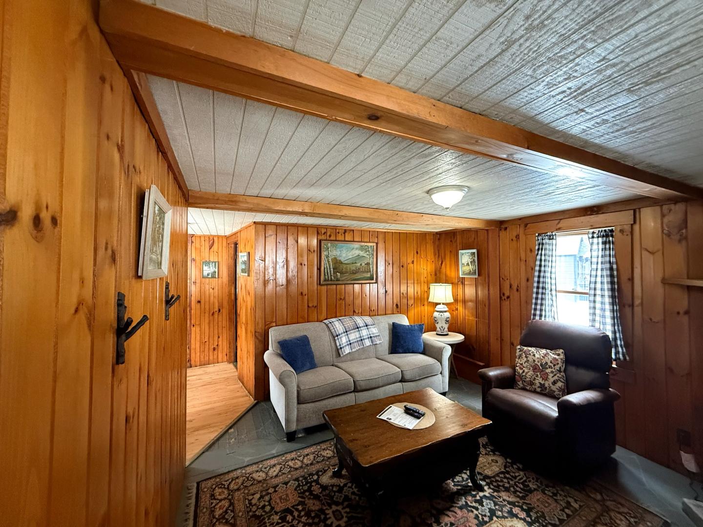 Cozy wood-paneled living room with a sofa, armchair, and coffee table.