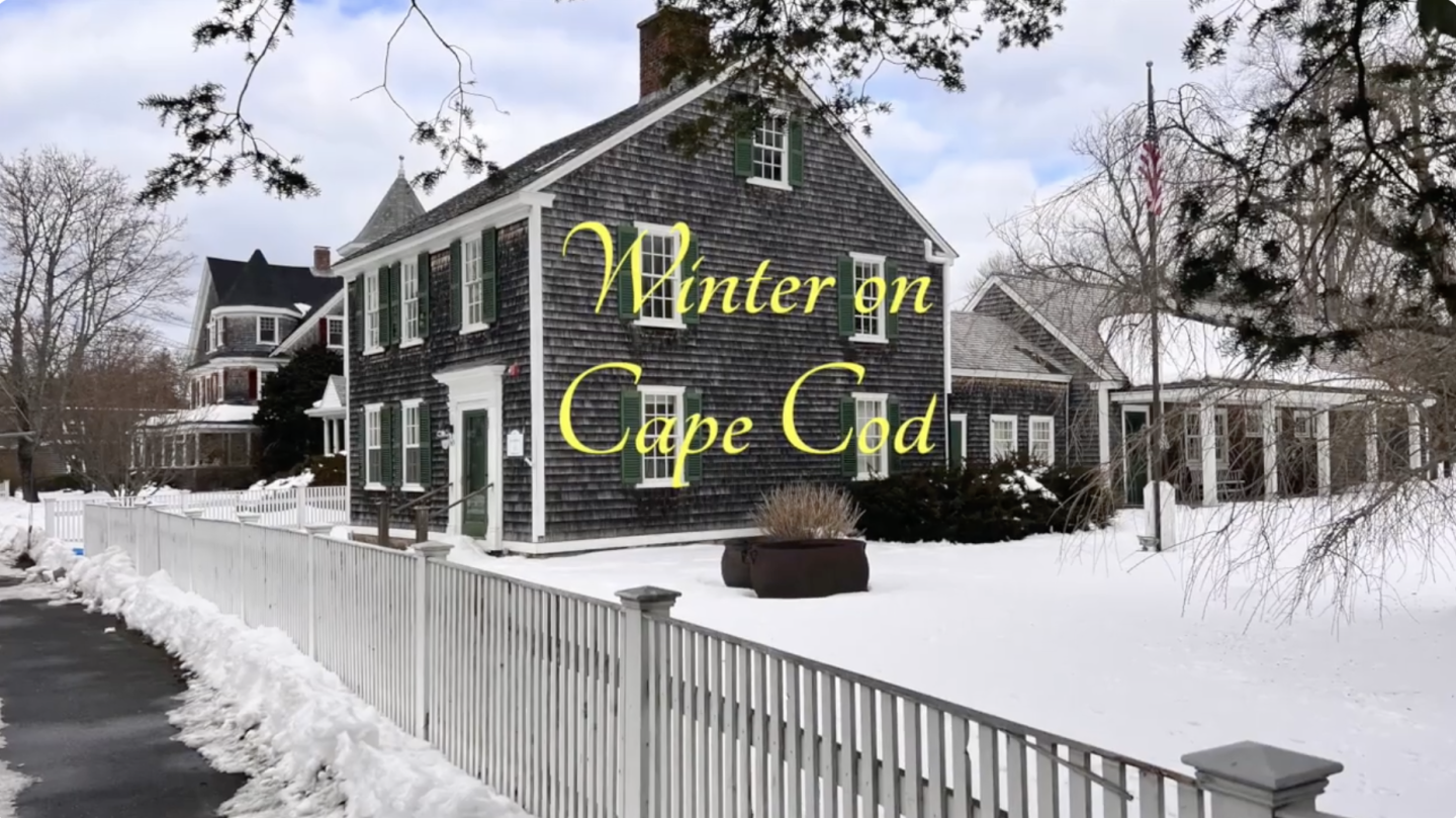 Snow-covered house and yard with a white picket fence at Palmer House Inn in Falmouth, MA near Cape Cod