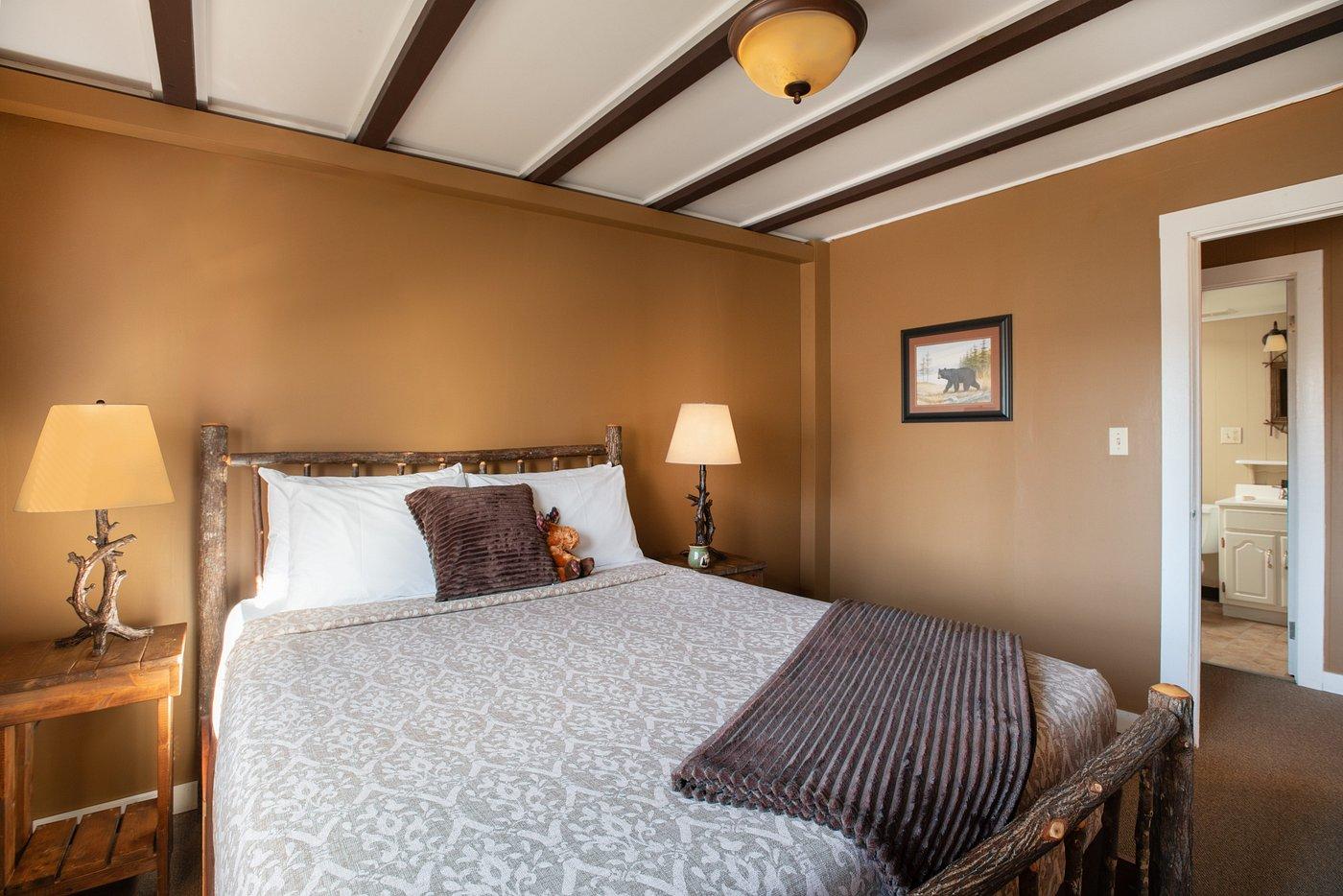 Cozy bedroom with a large bed, brown walls, and warm lighting.