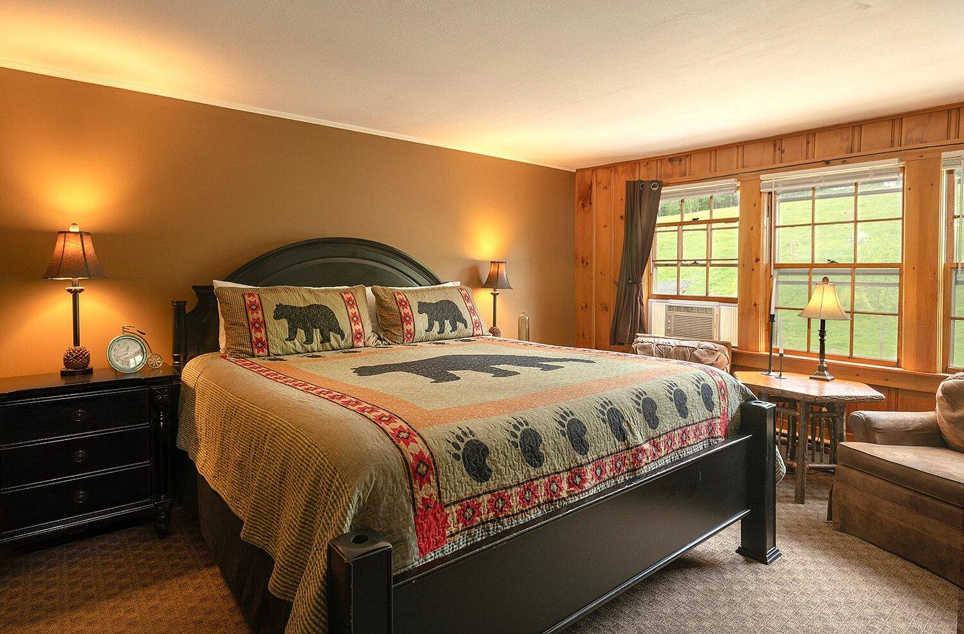 Cozy bedroom with bear-themed bedding, warm lighting, and large windows.