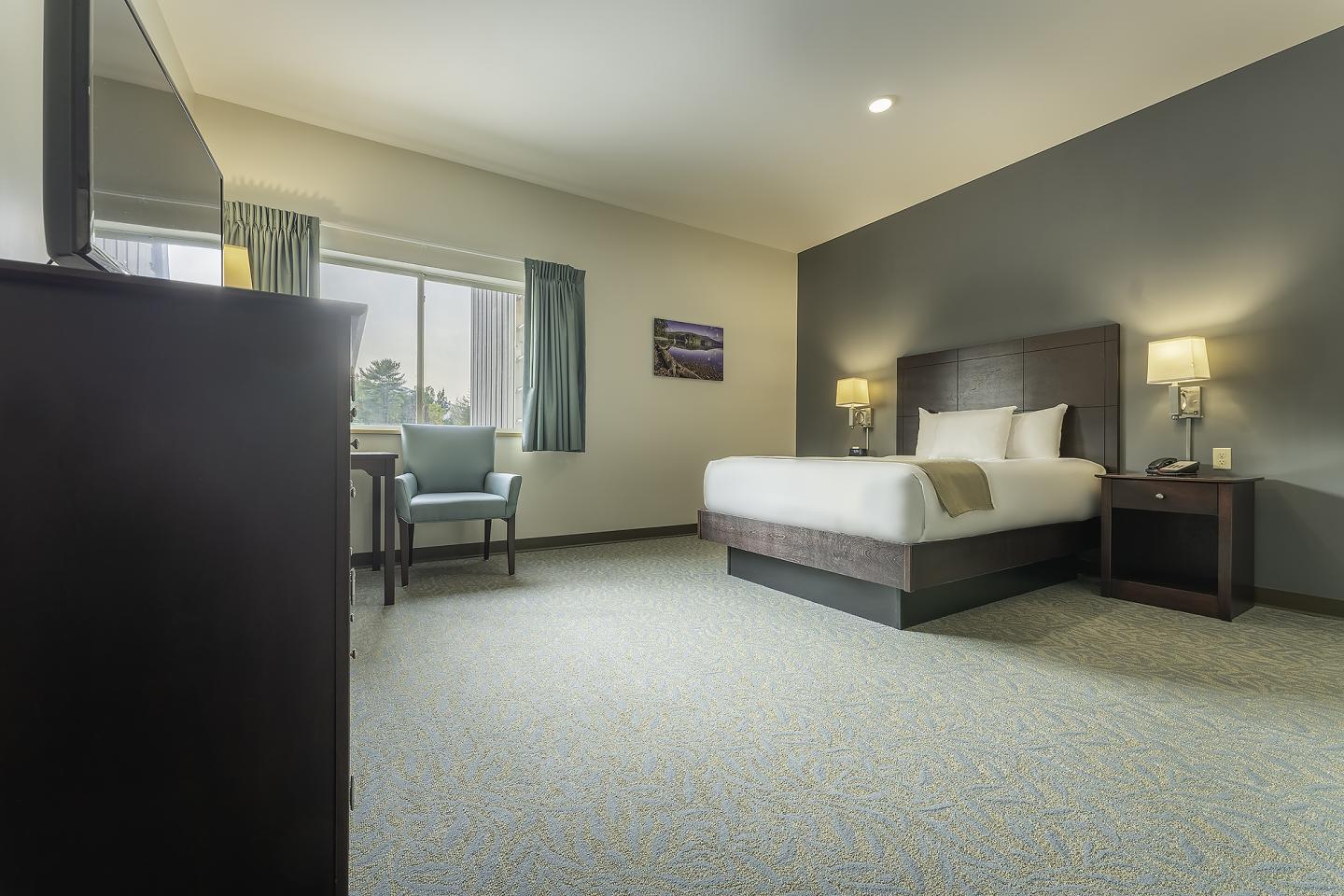 Spacious hotel room with double bed, desk, and lamps.