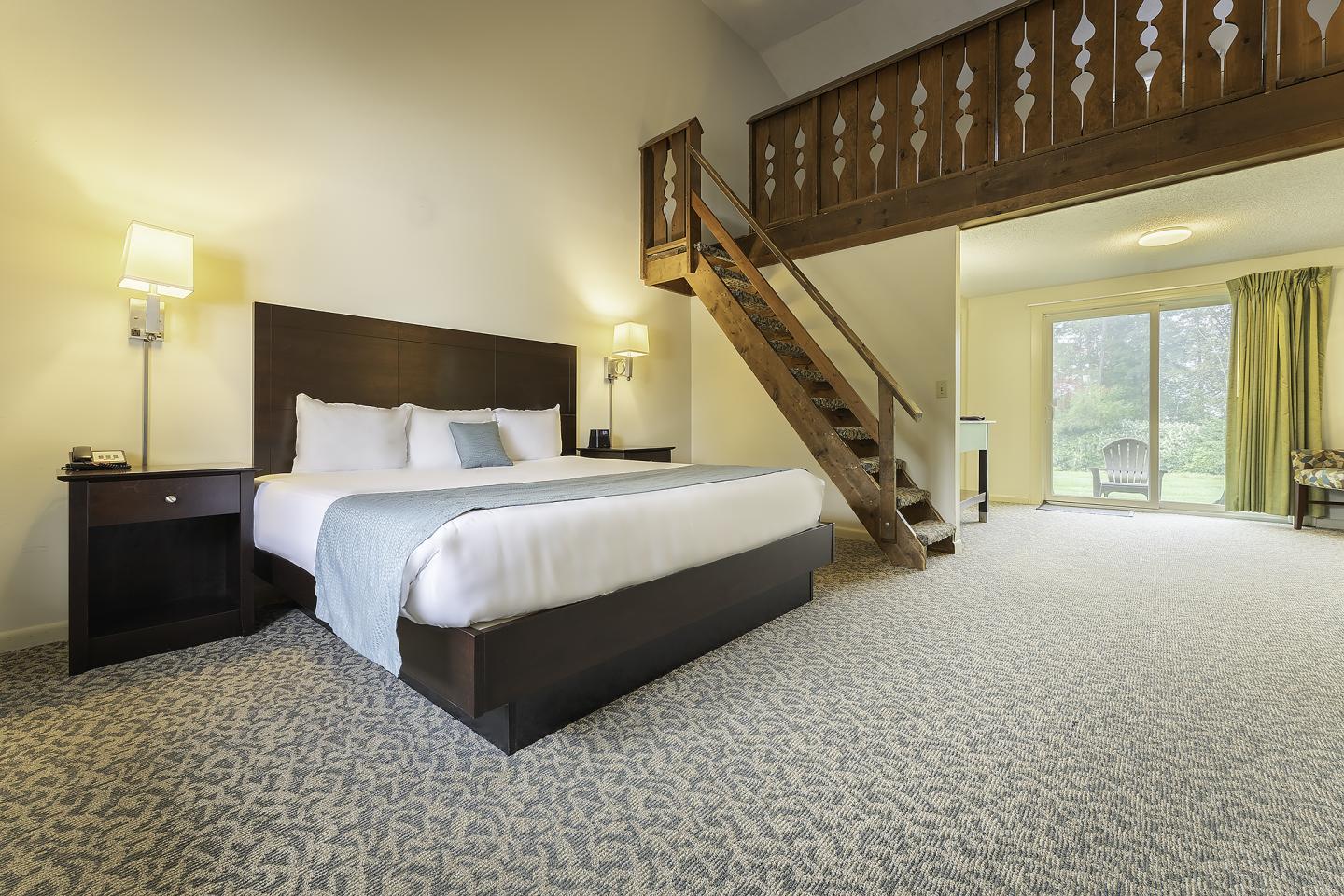 Spacious hotel room with a bed, loft, and large window.