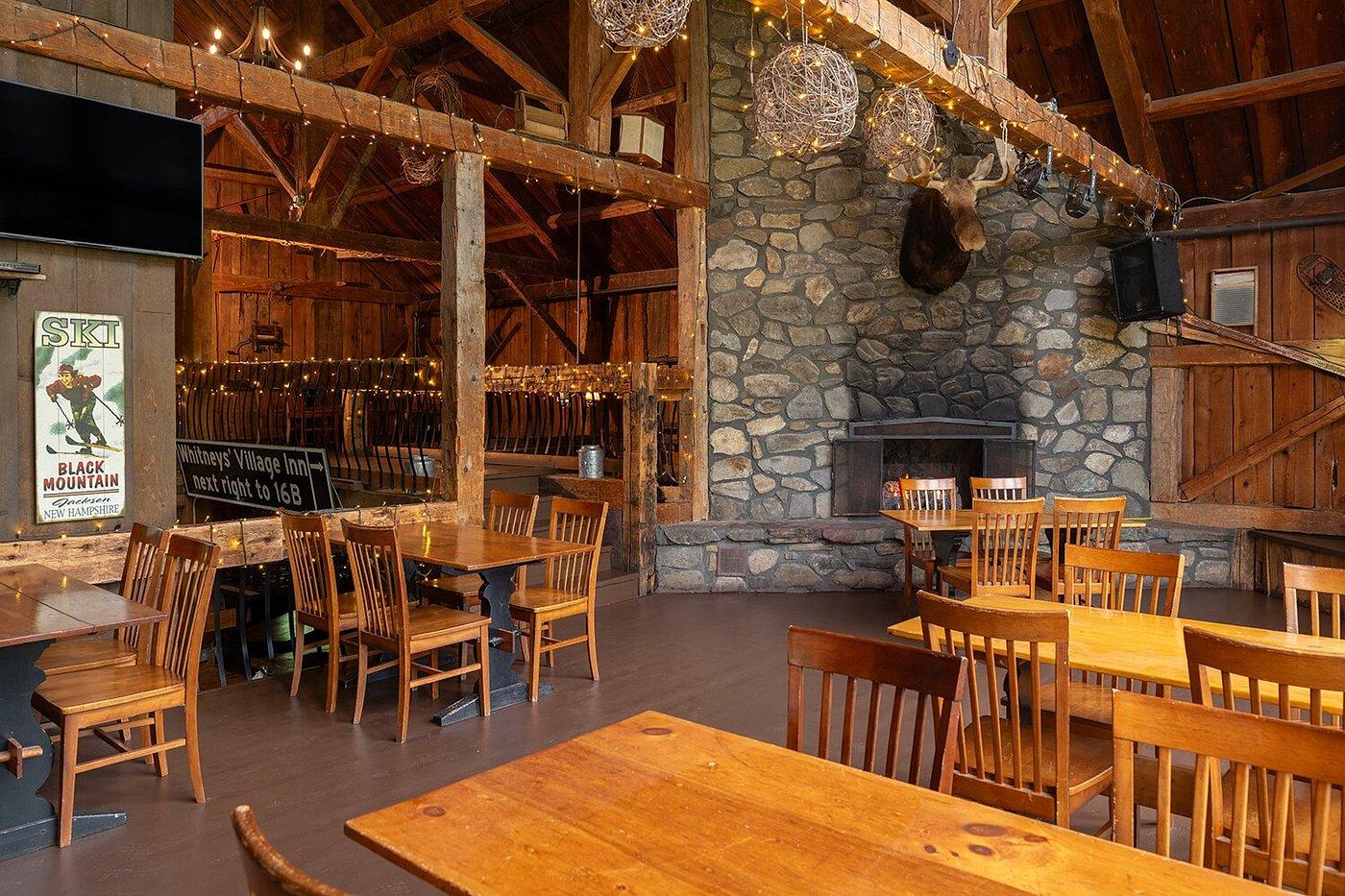 Cozy restaurant with wooden tables, stone fireplace, and warm lighting.