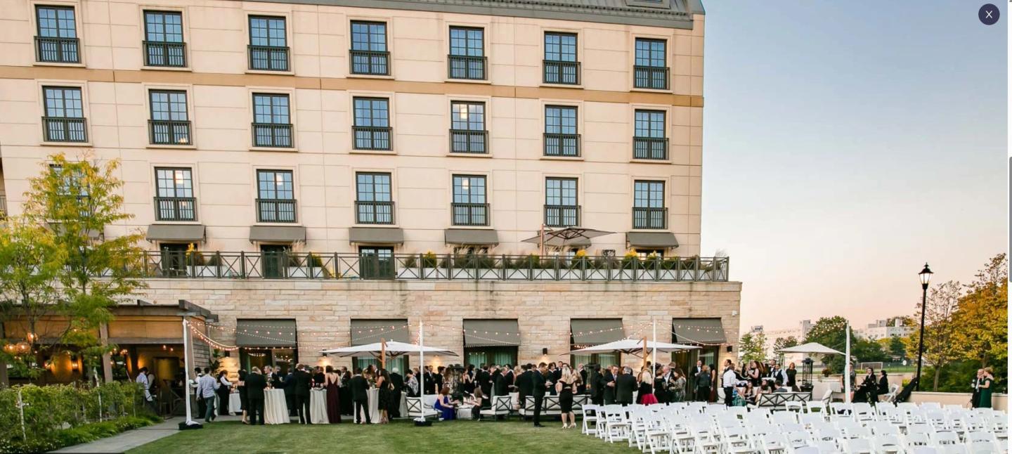 Guests gather outside a hotel for an event at sunset.