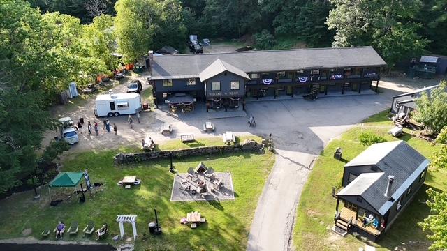 Aerial view of a campground with buildings, tents, and trees.