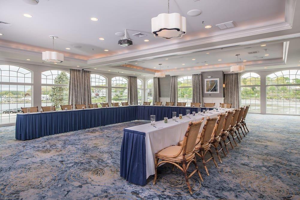 Spacious conference room with U-shaped table, blue carpet, and large windows.
