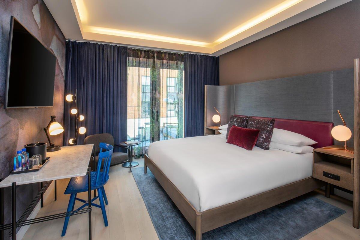 Hotel room with a large bed, desk, and modern decor.