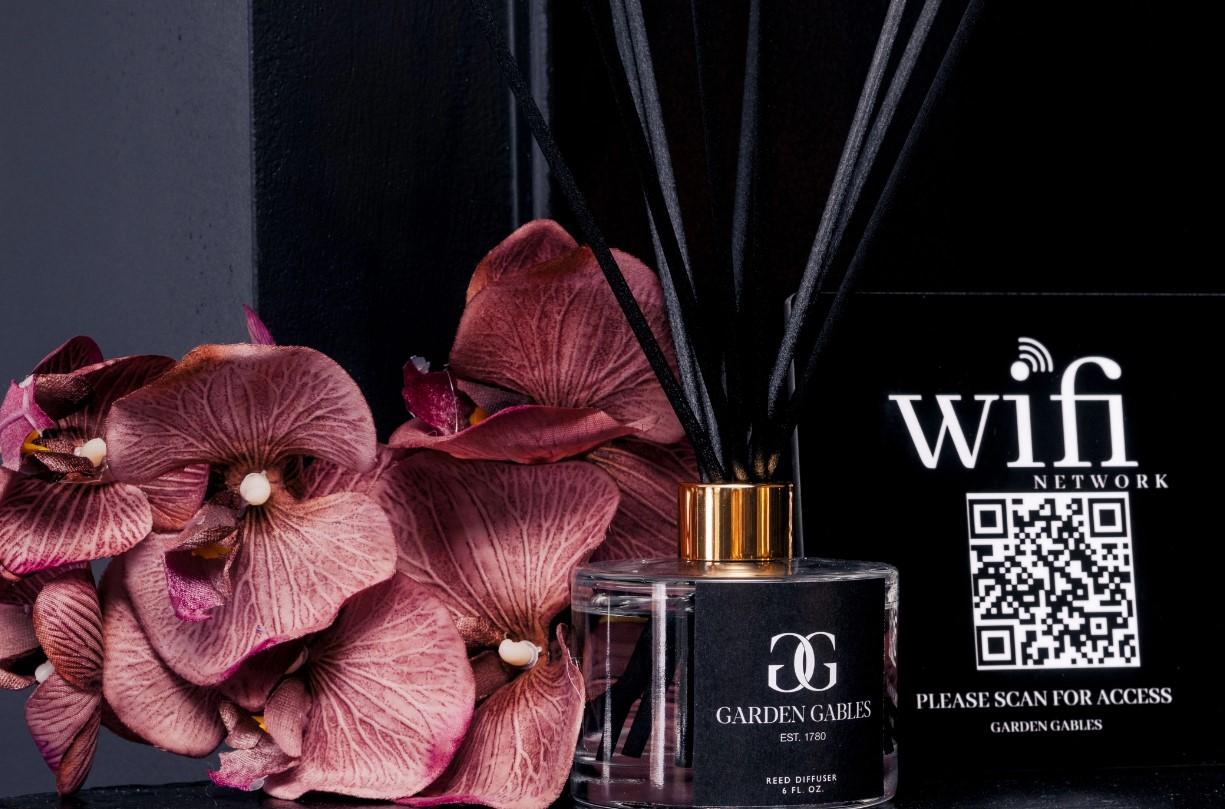 Fragrance diffuser with pink flowers and a QR code on a dark background.