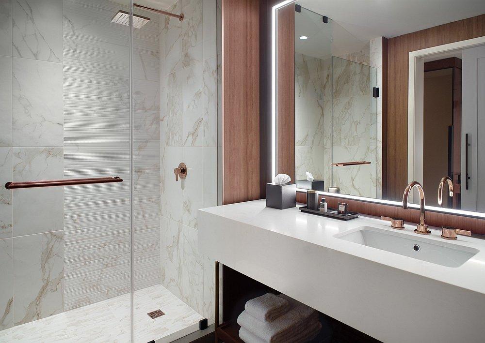 Modern bathroom with marble shower, large mirror, and white vanity.