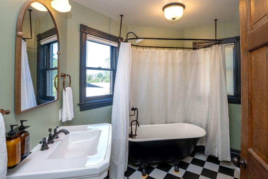 Cozy bathroom with a clawfoot tub, checkered floor, and round mirror.