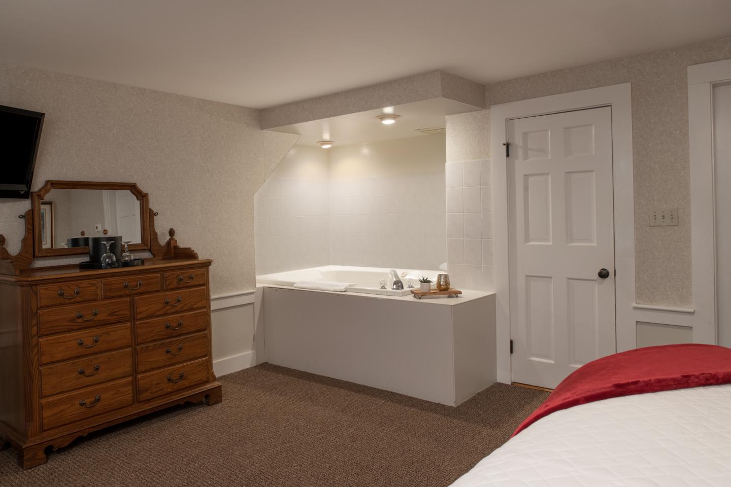 Bedroom with a wooden dresser, TV, and a white jacuzzi spa corner.