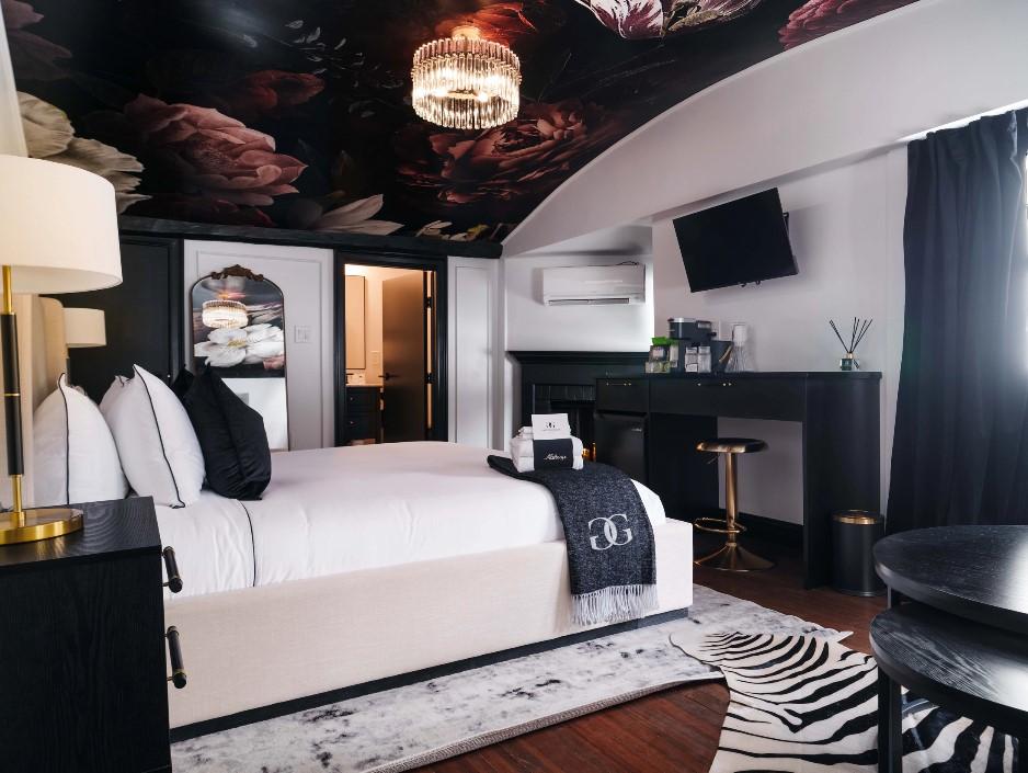 Elegant hotel room with a white bed, floral ceiling, and dark furnishings.