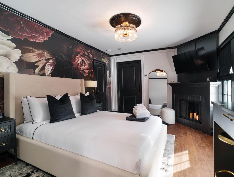 Elegant bedroom with floral wallpaper, white bed, black accents, and a wall-mounted TV.