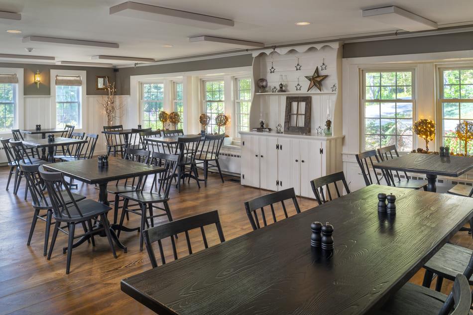 Spacious dining room with wooden tables and chairs, bright windows.