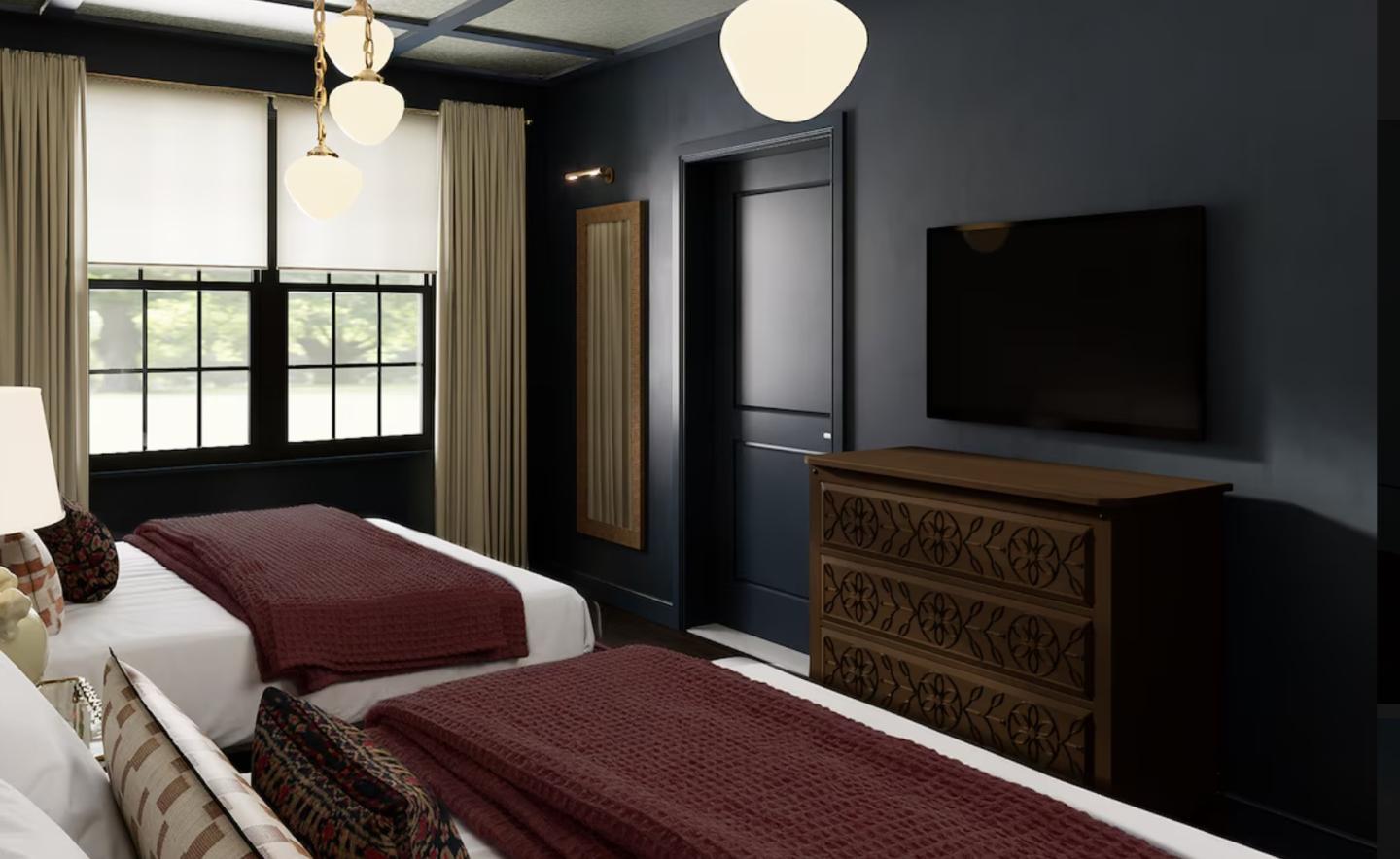 Two beds in a dark-toned room with a TV and dresser, lit by pendant lights.