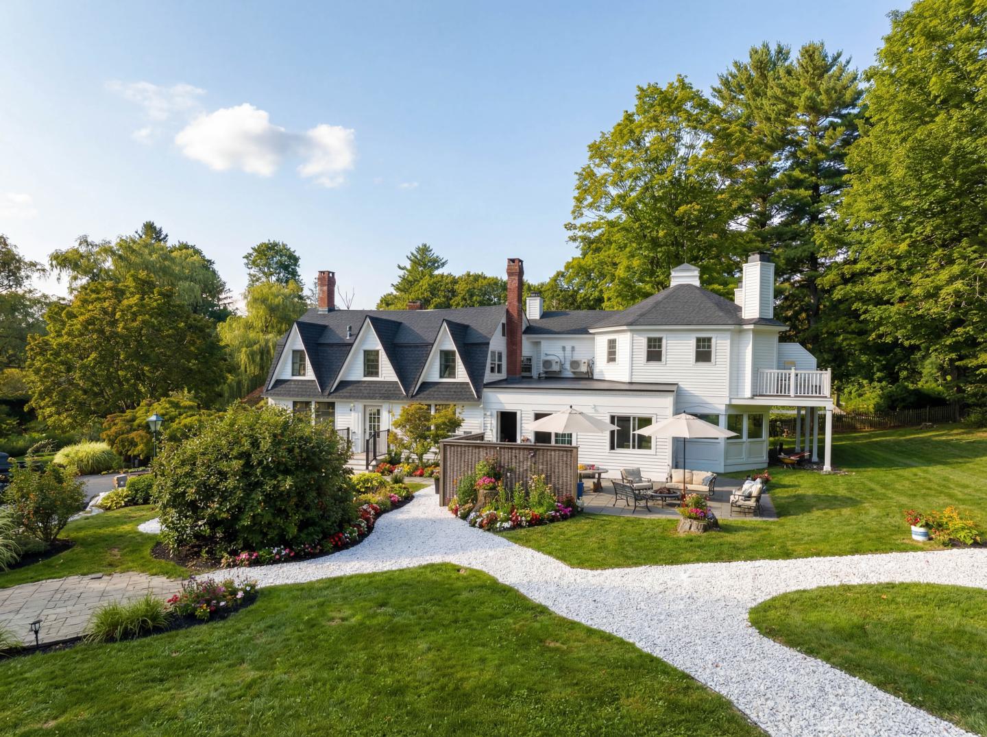 Large white house with manicured garden, trees, and curving gravel path.