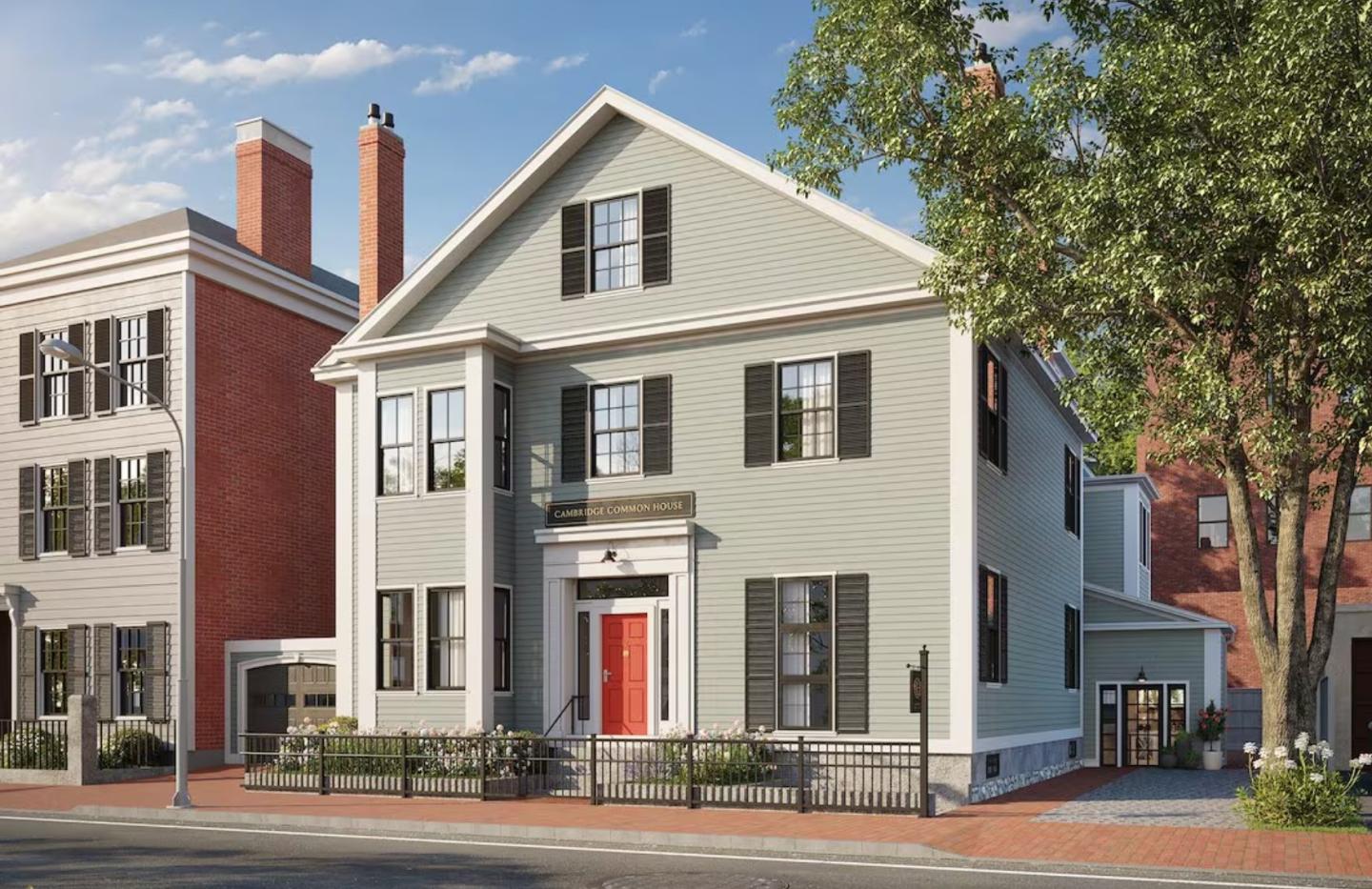 Historic house with red door, black shutters, and surrounding trees.