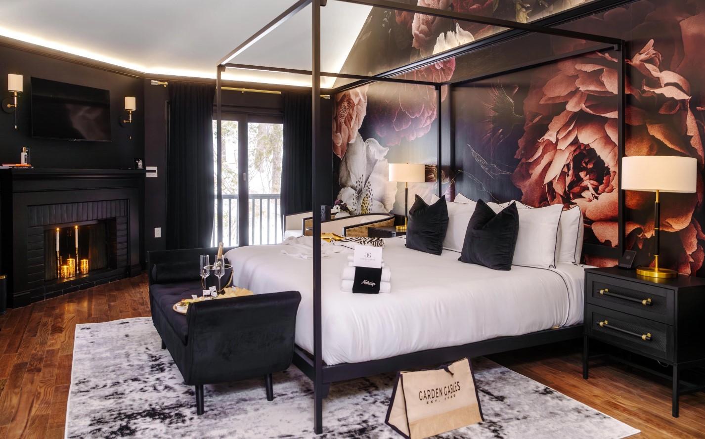 Luxurious bedroom with a canopy bed, floral mural, fireplace, and elegant decor.