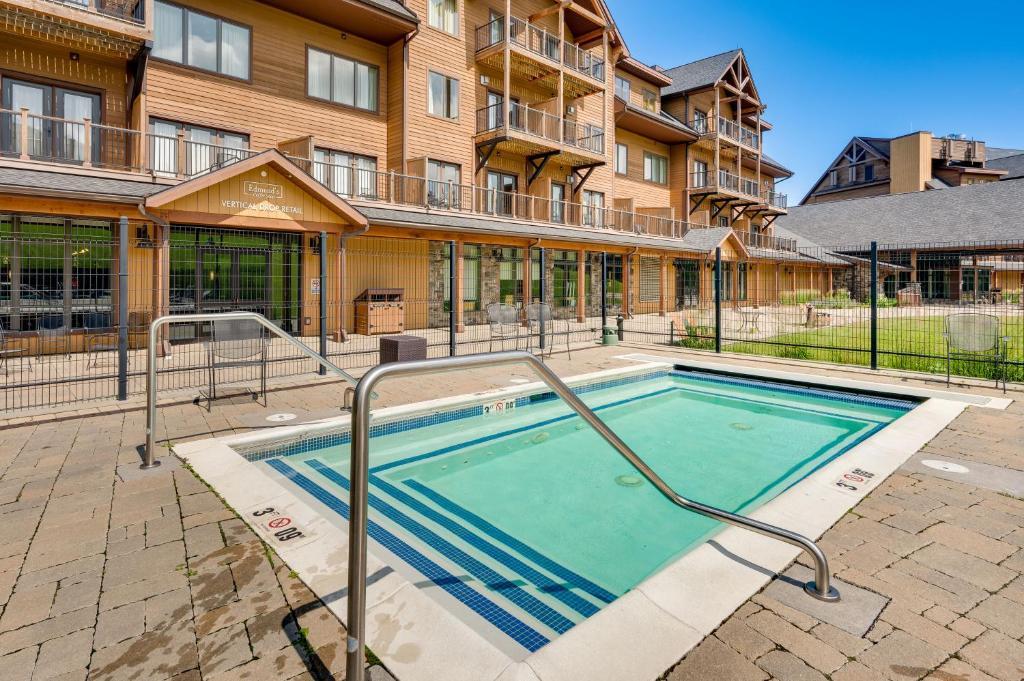 Outdoor pool with blue tiles and safety railings in front of a multi-story wooden building.
