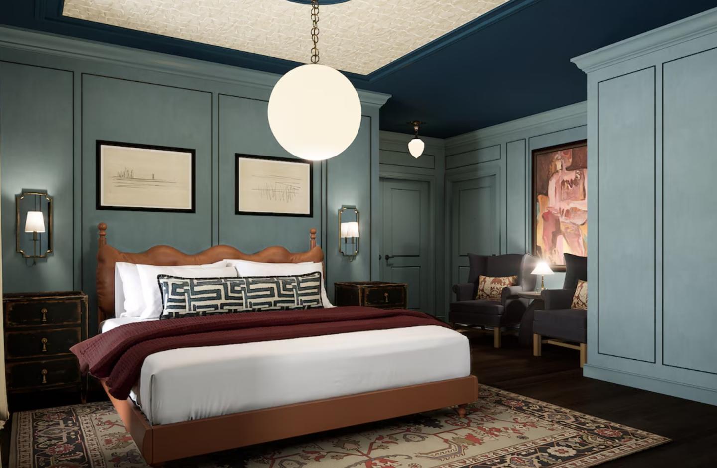 Elegant bedroom with a large bed, blue walls, and a white globe light.