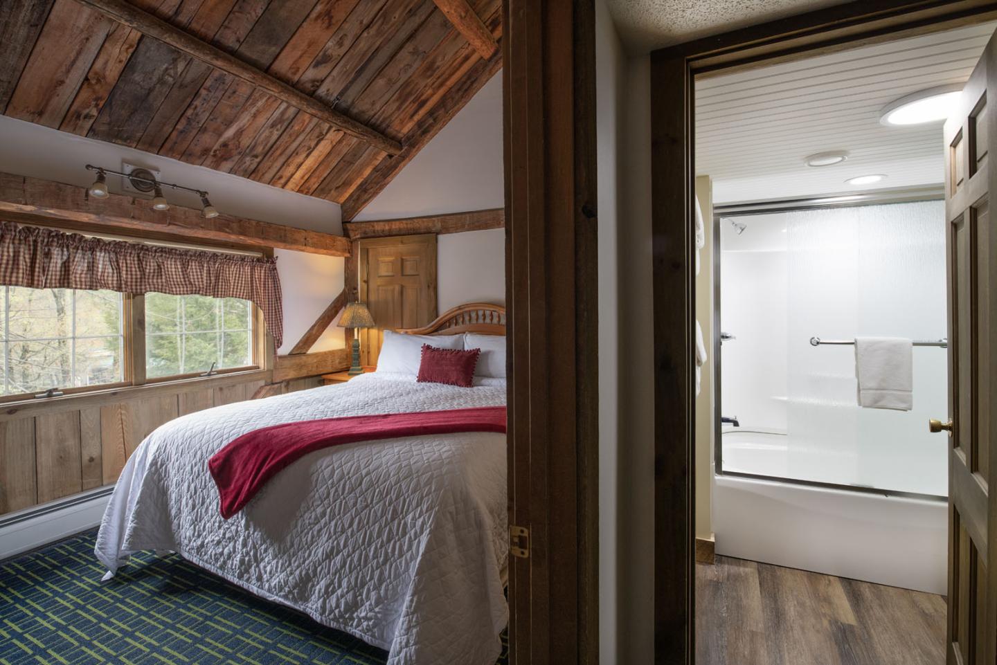 Cozy attic bedroom with rustic decor and adjacent modern bathroom.