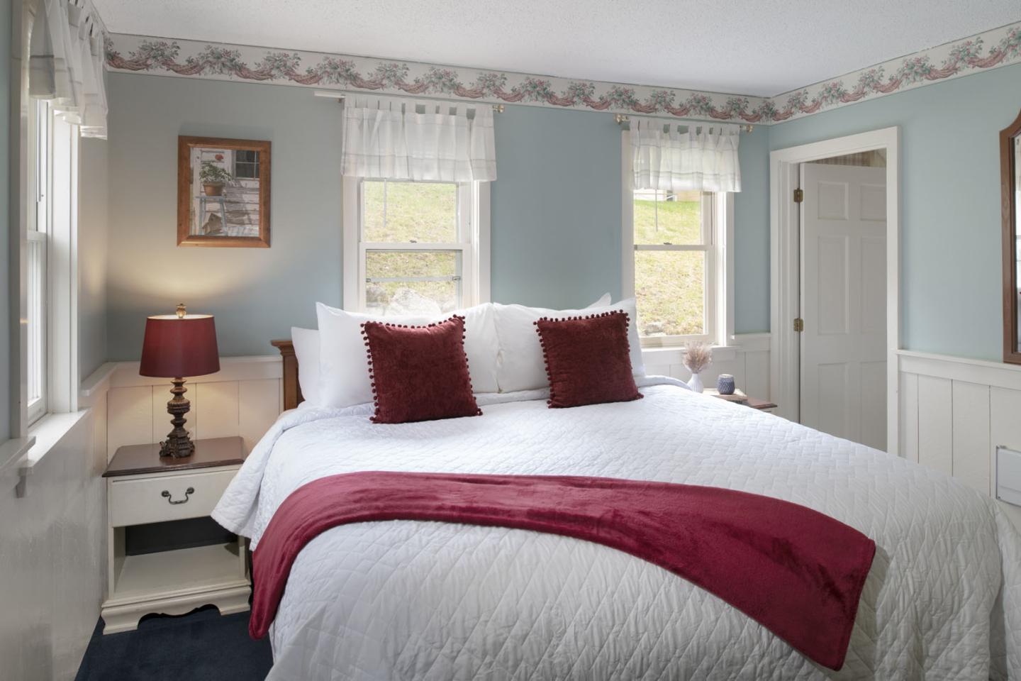 Cozy bedroom with a large bed, red accents, and soft lighting.