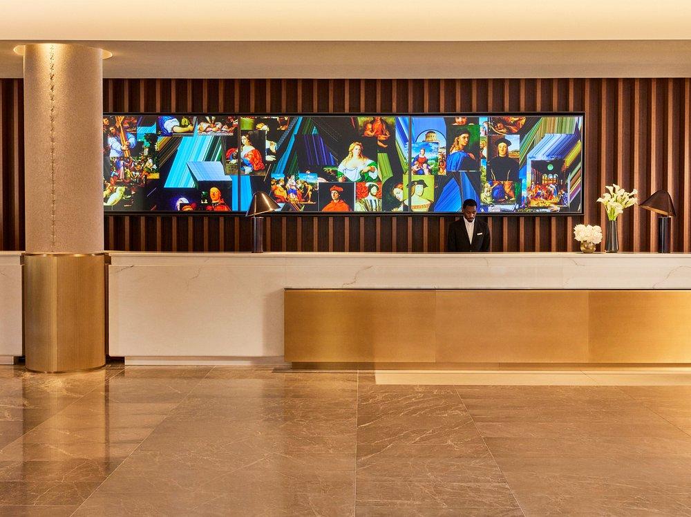 Hotel lobby with a modern reception desk and colorful artwork above.