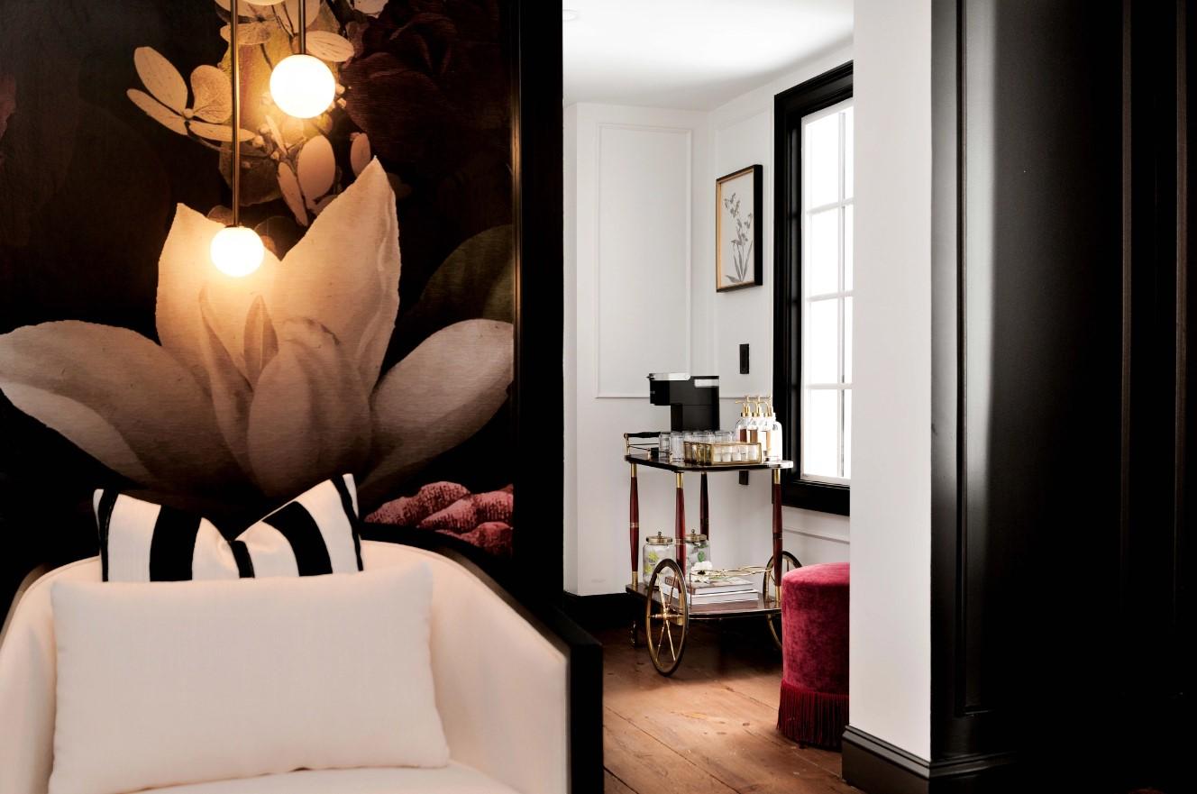 Modern interior with floral mural, cozy chair, and bar cart by a window.