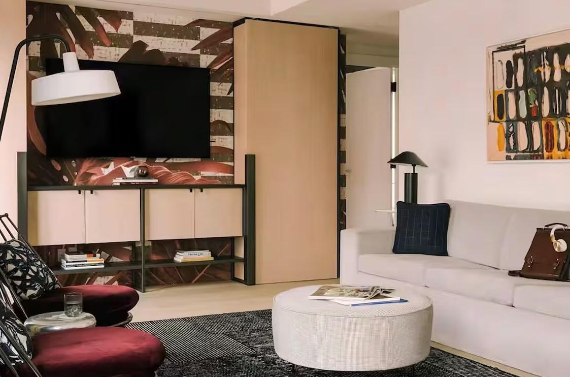 Modern living room with a white sofa, abstract art, and a flat-screen TV.