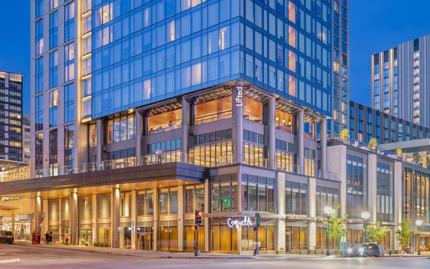 Modern glass building with warm lights at dusk.