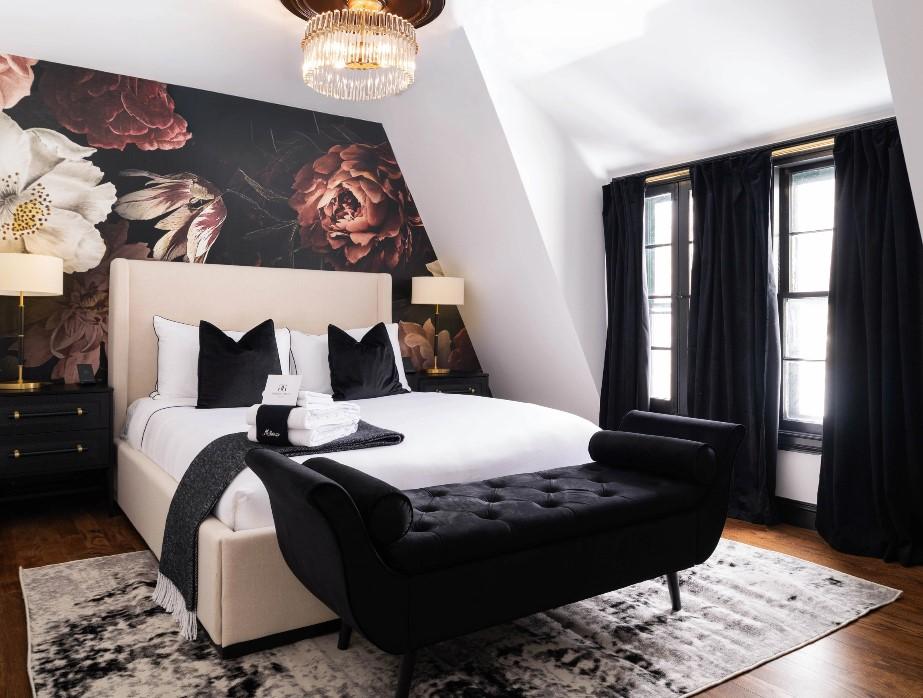 Elegant bedroom with floral mural, black curtains, and plush bedding.