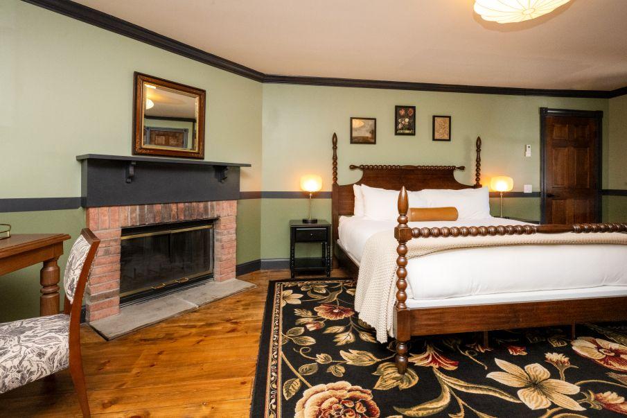 Cozy bedroom with a fireplace, wooden furniture, and floral rug.