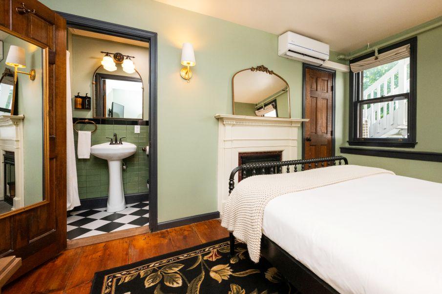 Cozy bedroom with a white bed, a fireplace, and an en-suite bathroom with black-and-white tiles.