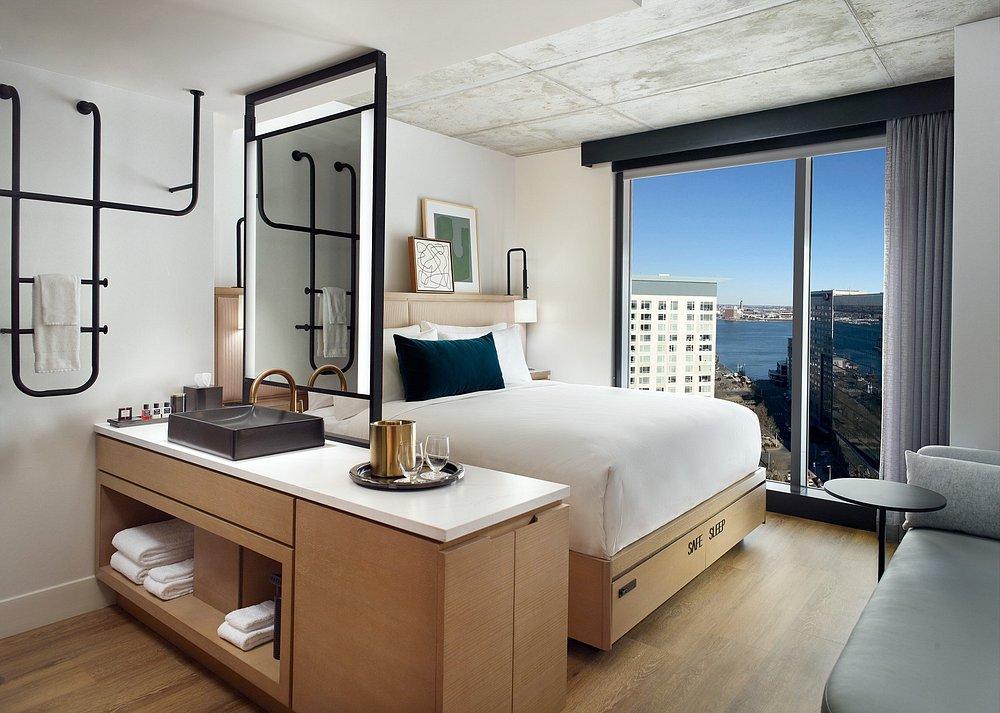 Modern hotel room with a bed, large window, and city view.