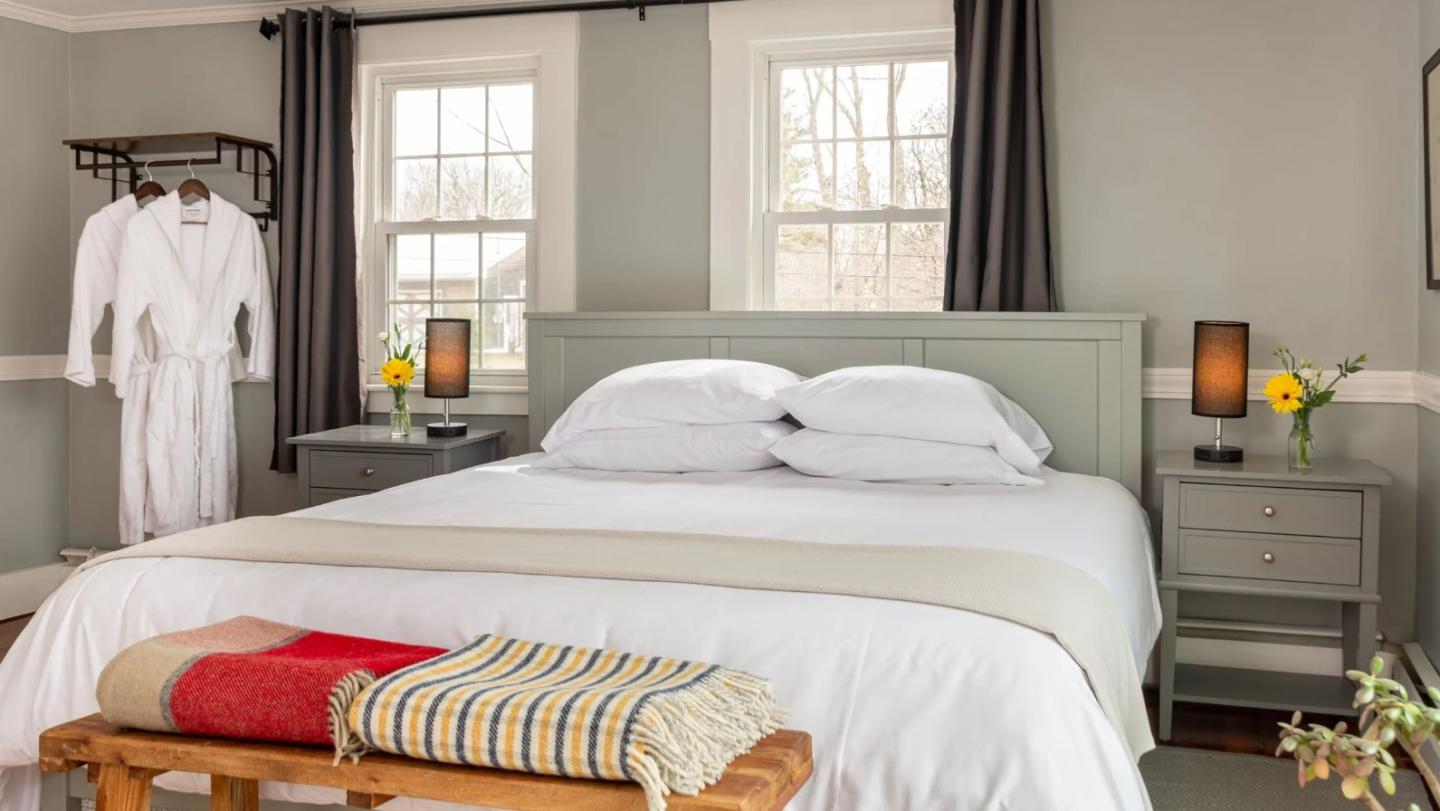 Cozy bedroom with king bed, robes, flowers, and warm lighting.