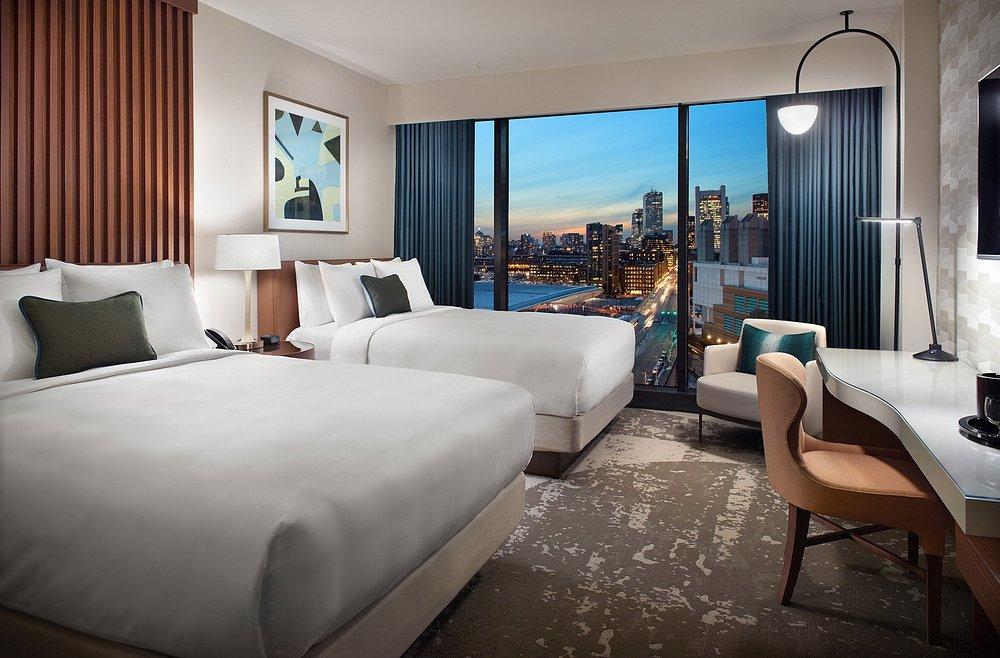 Hotel room with two beds, a city view, and a modern interior design.