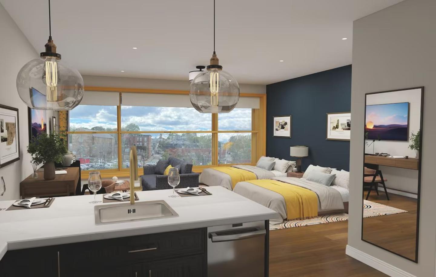 Modern studio apartment with bed, sofa, and kitchen island, large windows in the background.