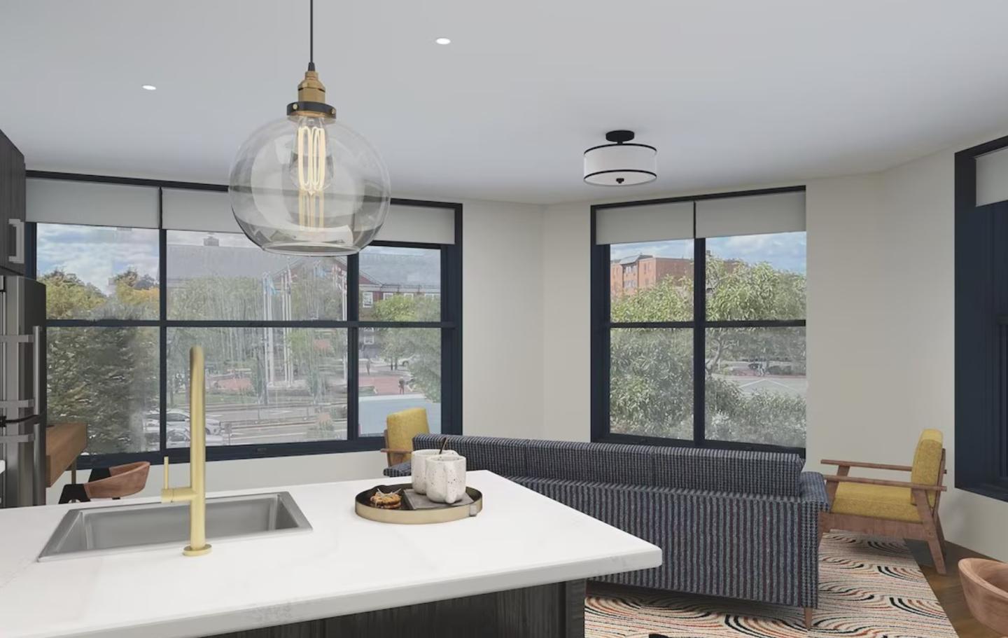 Modern living room with large windows, a kitchen island, and gray couch.