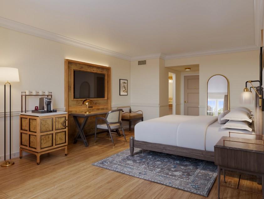 Cozy hotel room with a large bed, desk, and soft lighting.