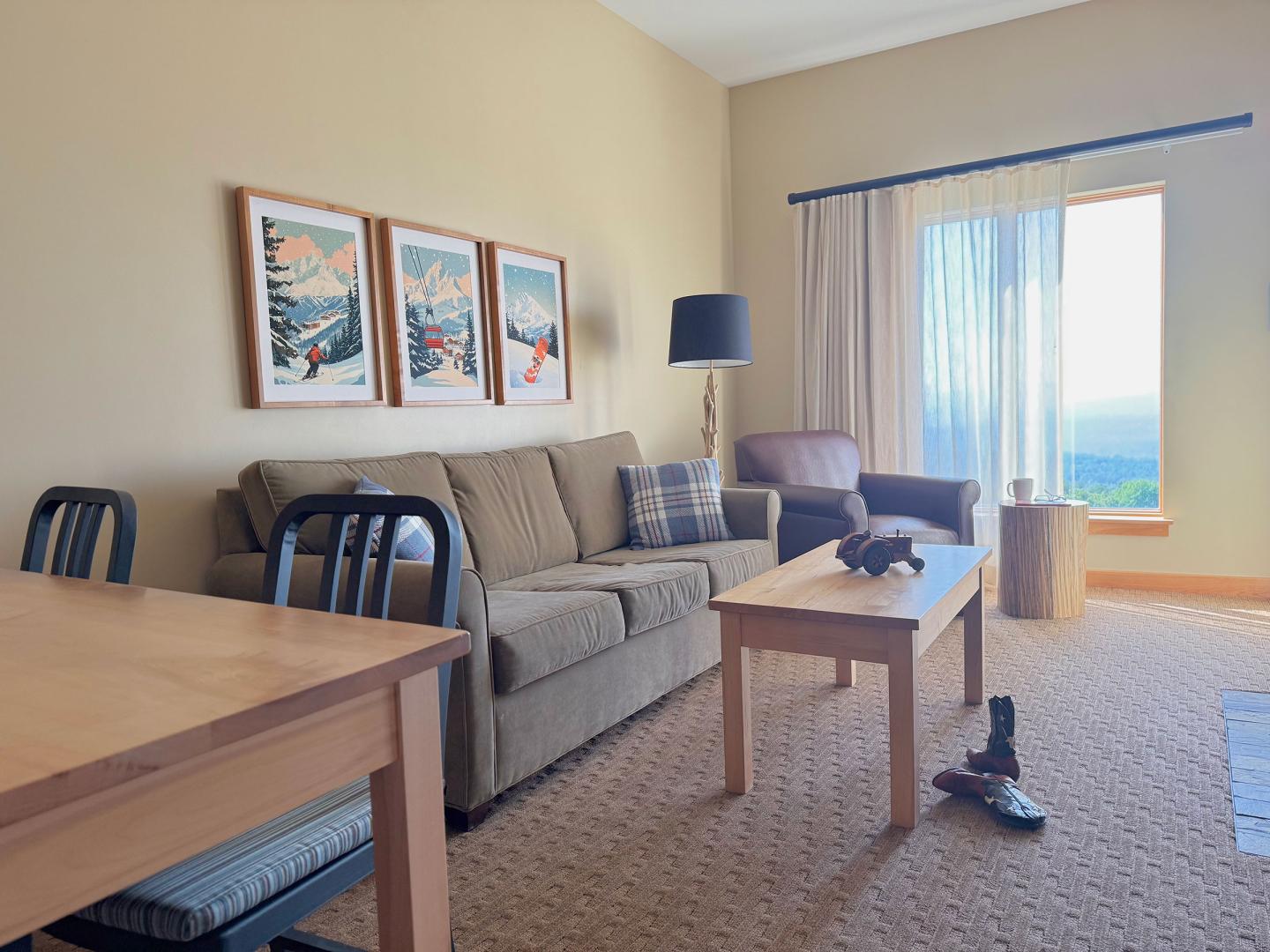 Cozy living room with a sofa, armchair, and table near a large window.