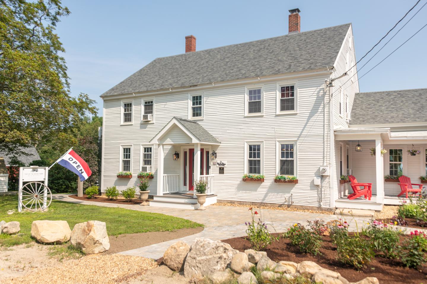 White two-story house with a garden and a flag in front.