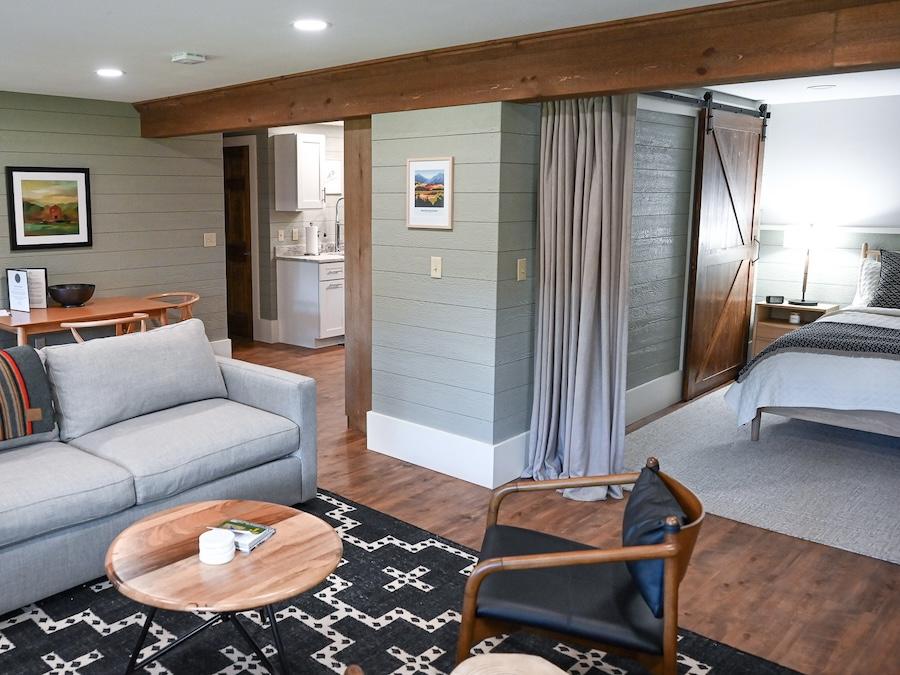 Cozy living room with gray sofa, wooden table, and adjacent bedroom.