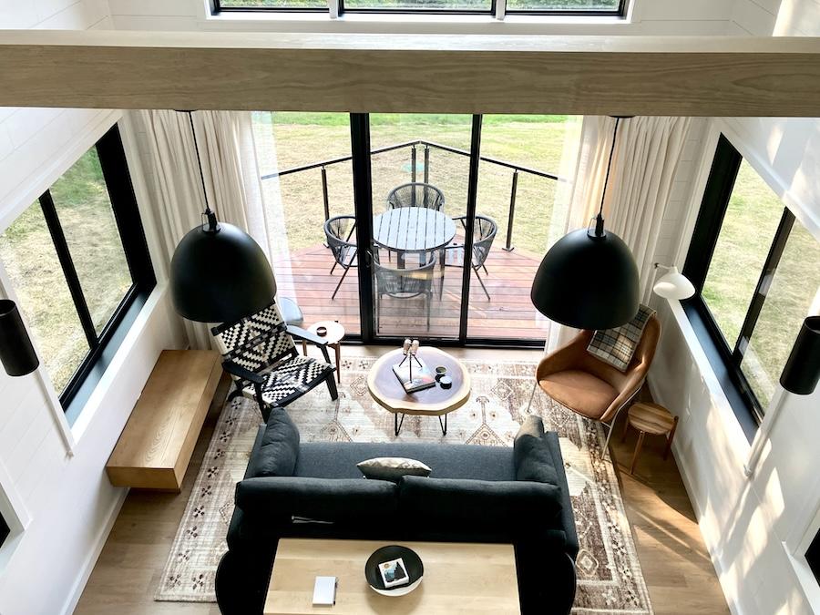Cozy living room with large windows, black couch, and outdoor view.
