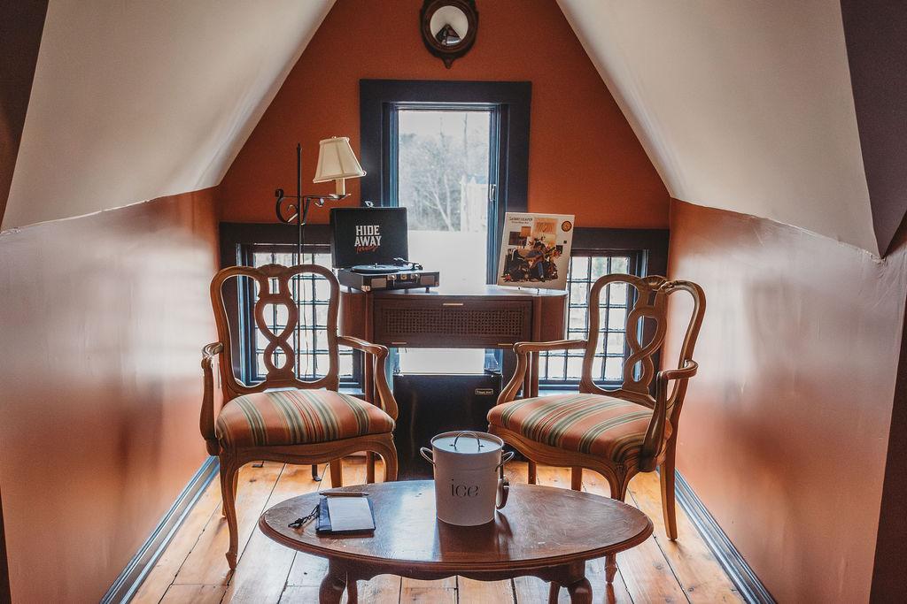 Cozy attic room with two chairs, a small table, and a record player.